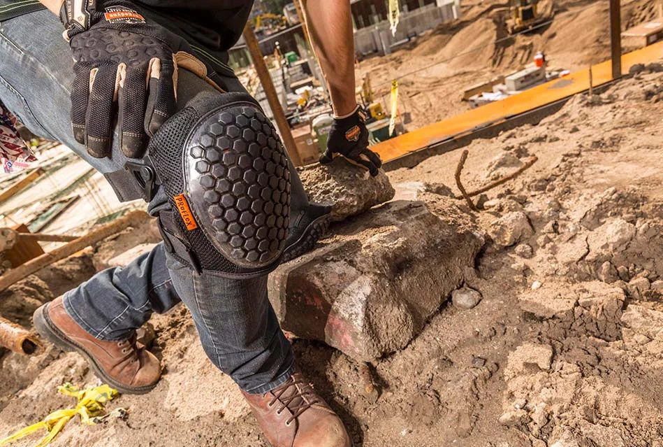 Worker wearing Ergodyne knee pads while lifting rocks on a construction site for safety protection – Pryme Australia.