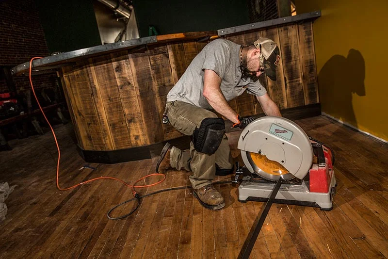 Tradesman using Ergodyne knee pads while cutting flooring material indoors – Pryme Australia safety gear.