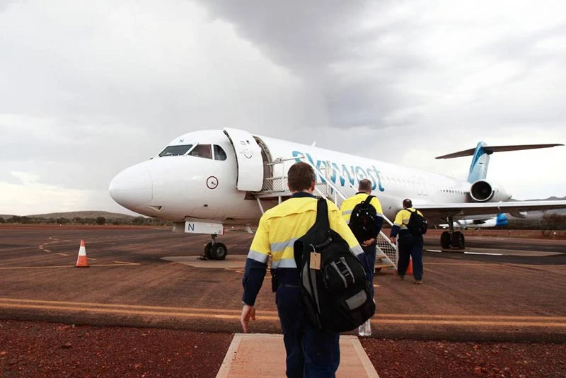 FIFO workers boarding aircraft, highlighting dehydration risks and workplace hydration solutions by Pryme Australia.