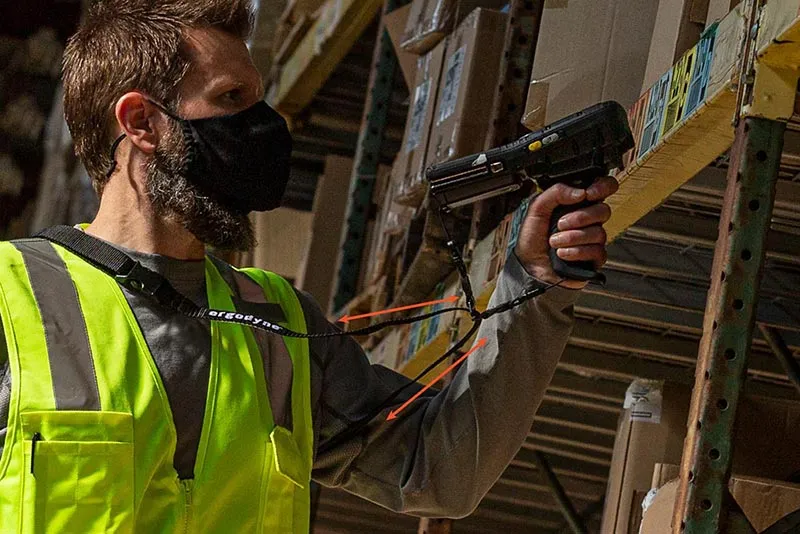 Warehouse worker using handheld scanner while wearing Pryme safety gear to ensure full range of motion.