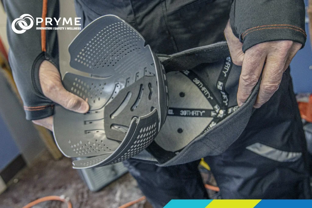 Worker fitting Ergodyne knee pads into work pants, demonstrating durable ergonomic protection.