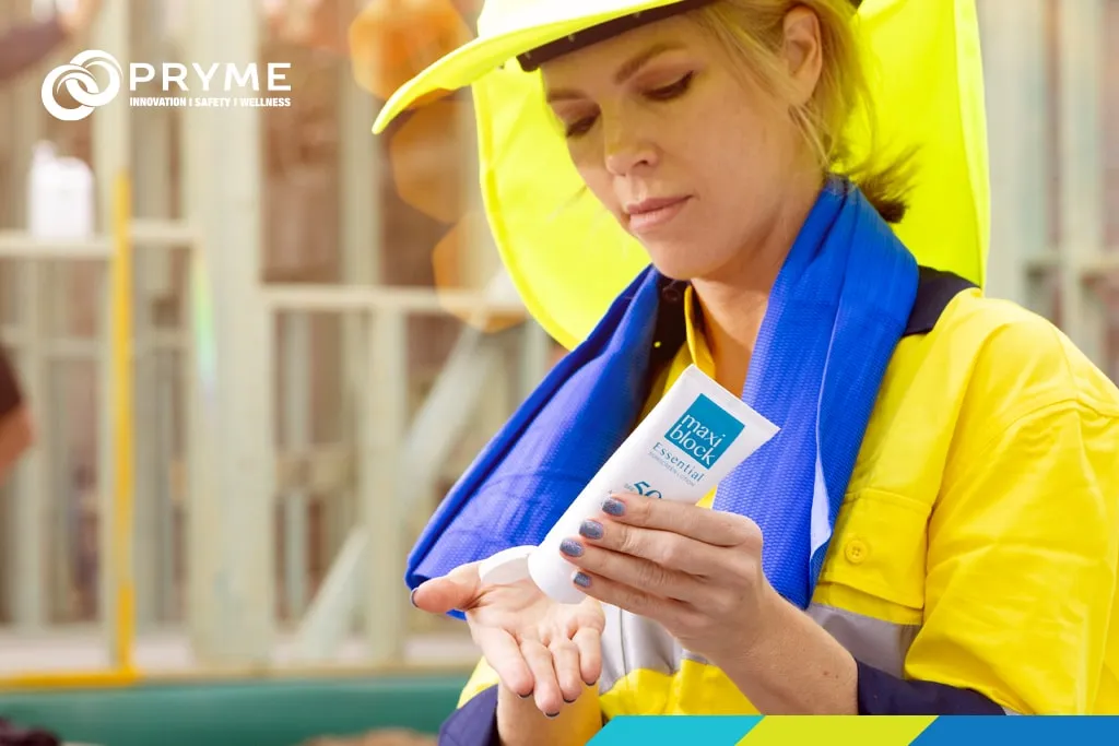 Construction worker applying Maxiblock SPF50+ sunscreen while wearing sun protection clothing on site.