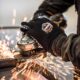 Worker wearing Ergodyne ProFlex 9000 gloves while grinding metal for hand protection against sparks and vibration.