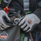 Worker wearing gloves attaching carabiner to Ergodyne Arsenal 5928 bolt bag using reinforced loop.