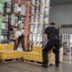 Workers lifting boxes in warehouse while wearing Ergodyne ProFlex back support belts for safe manual handling.