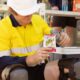 Worker in high-vis uniform mixing Sqwincher Fast Pack electrolyte pouch with water on-site.