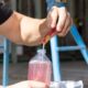 Close-up of worker pouring Sqwincher Zero Qwik Stik electrolyte powder into water bottle.
