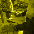 Worker writing safety checklist on clipboard, stylised in yellow Pryme brand filter.